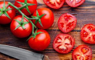 Fresh tomatoes on wooden cutting board.