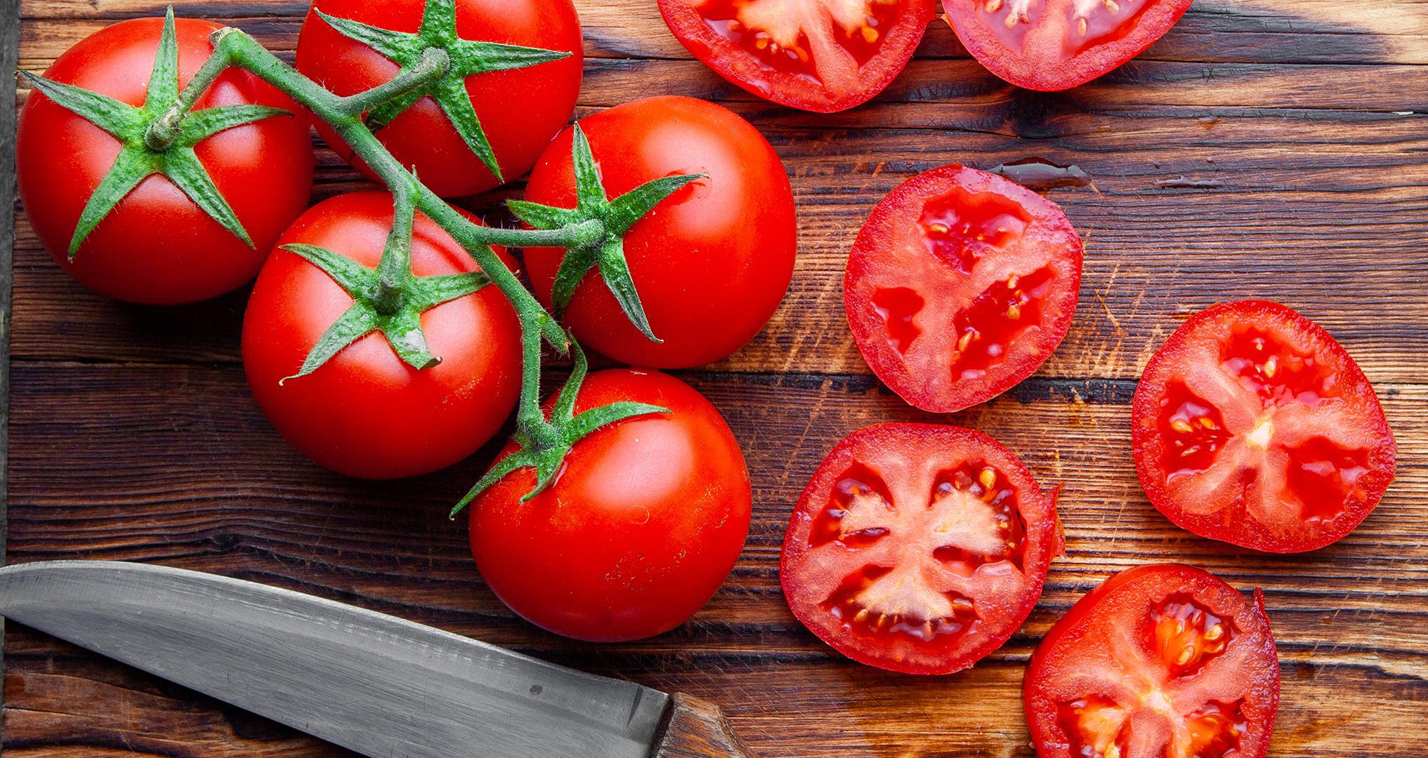 Fresh tomatoes on wooden cutting board.